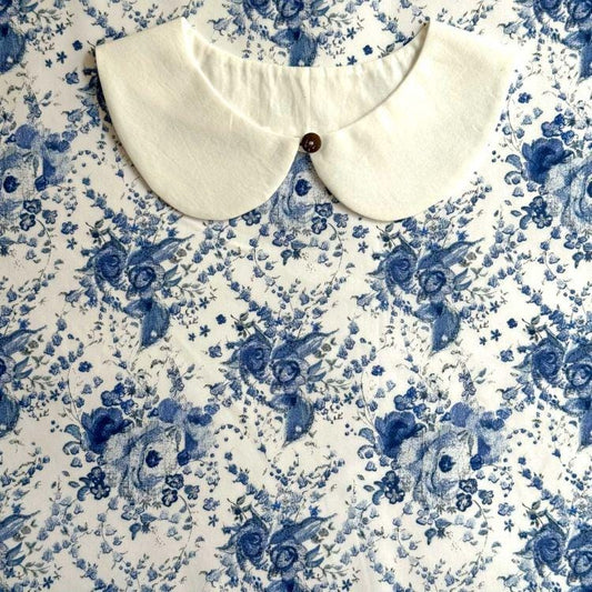 a white collar with a button, set against a background with a blue floral pattern.