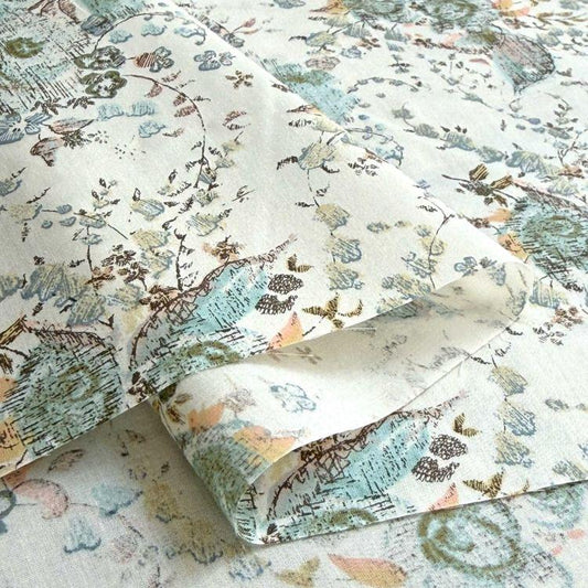 a close-up view of a fabric with a floral pattern, featuring various shades of green, blue, and brown.