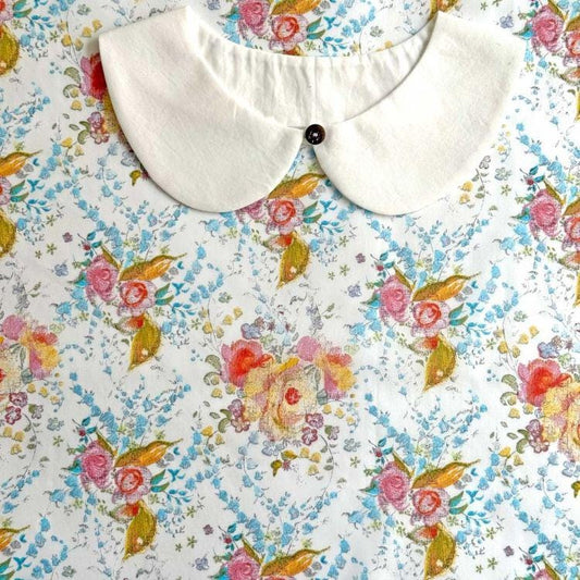 a white collar with a button, set against a background with a floral print.