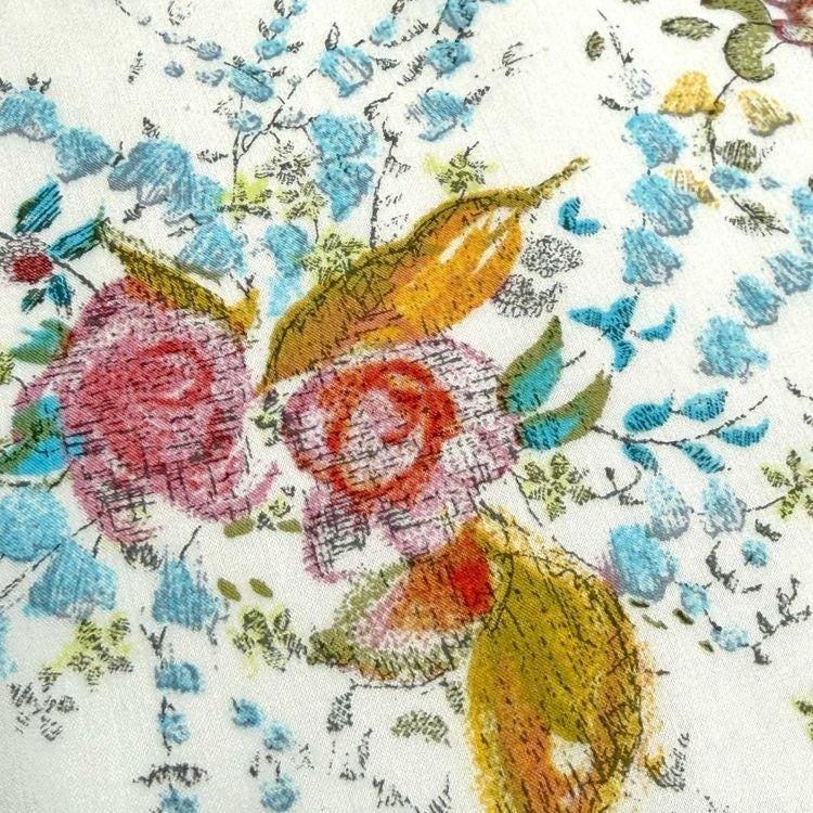 The image is a close-up of a fabric with a floral pattern, featuring a variety of colorful flowers and leaves.