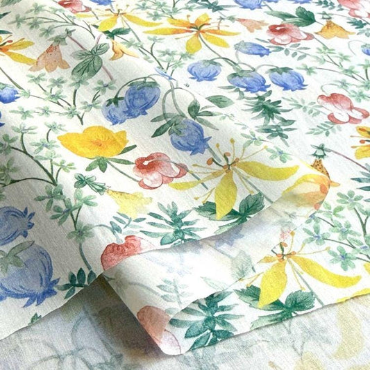 a close-up view of a fabric with a vibrant floral pattern. The fabric is adorned with a variety of colorful flowers, including yellow, blue, and pink blooms, as well as green leaves and stems. The pattern is intricate and detailed, showcasing the craftsmanship and artistry involved in creating the fabric.