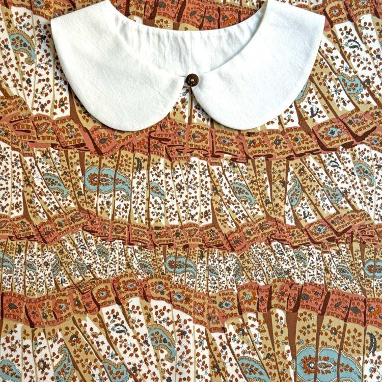 a close-up view of a white collar and a colorful, patterned fabric with a repeating design.