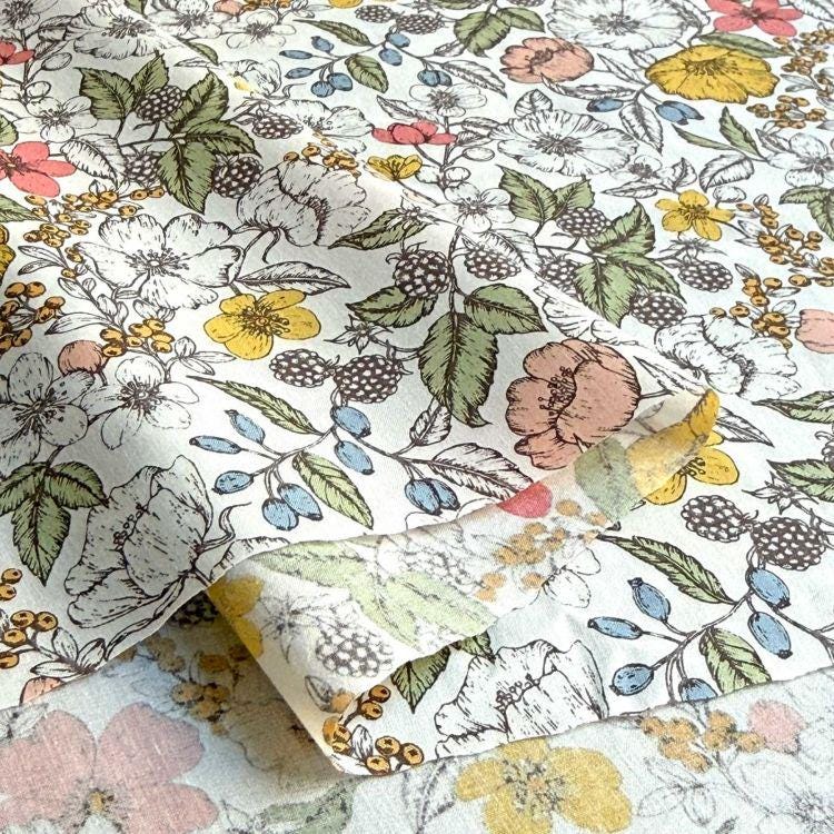 a close-up view of a fabric with a floral pattern. The fabric is adorned with various flowers, leaves, and berries in different colors, creating a vibrant and visually appealing design. The pattern is intricate and detailed, showcasing the craftsmanship and artistry involved in creating the fabric.