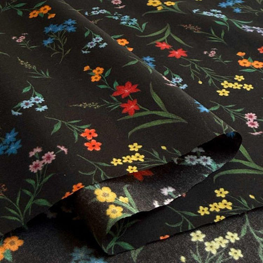 a close-up view of a fabric with a floral pattern in various colors, including red, orange, yellow, and blue. The fabric appears to be black, and the pattern is intricate and detailed.