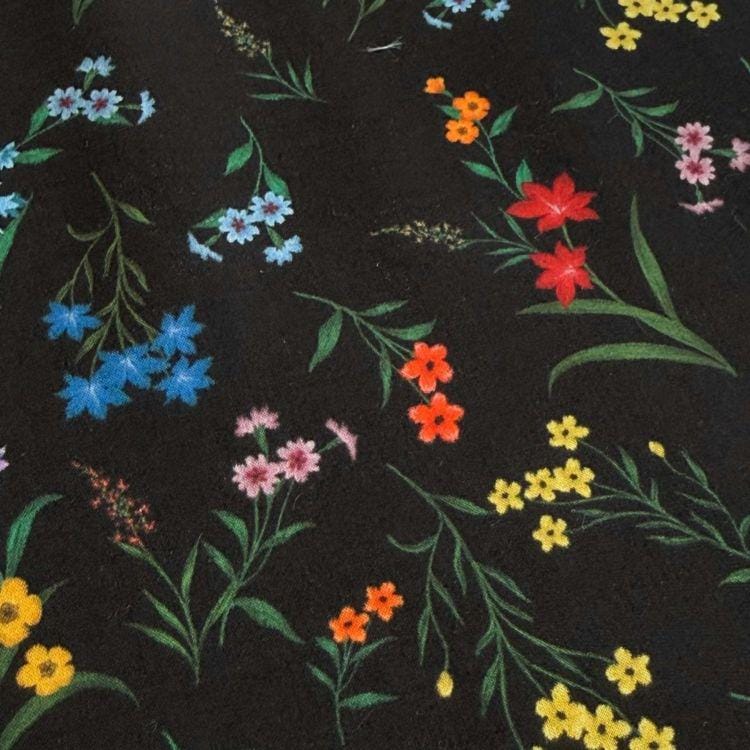a close-up view of a black background adorned with a variety of colorful flowers and leaves, including red, orange, yellow, and blue flowers.