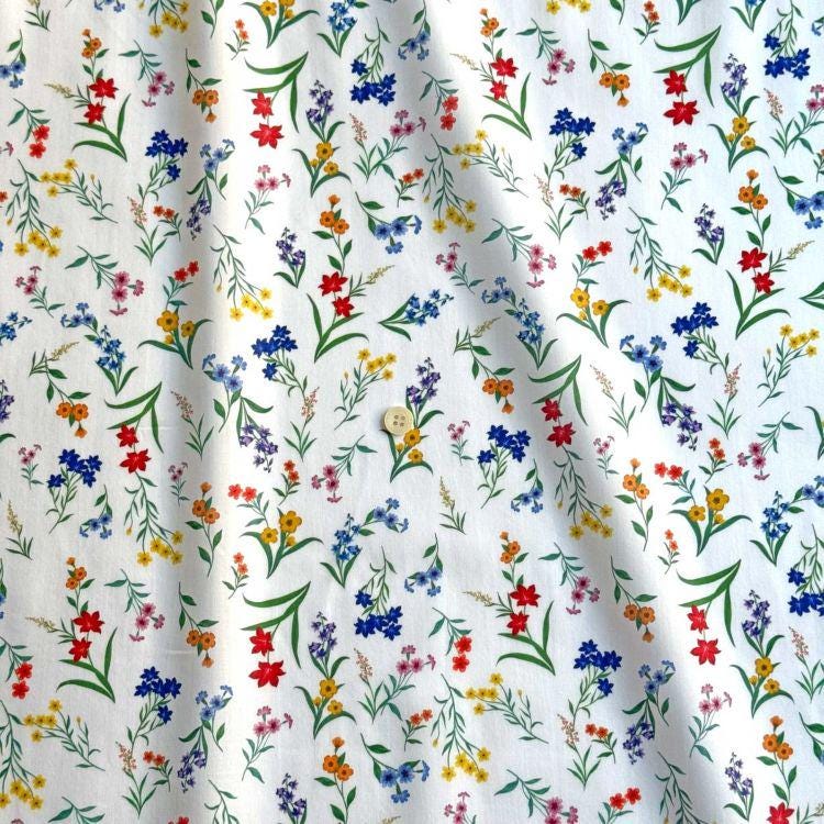 a white fabric with a repeating pattern of colorful flowers and leaves.