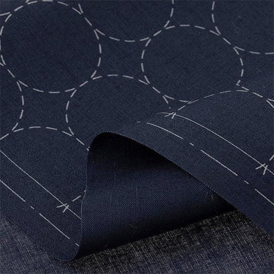 a close-up view of a dark blue fabric with a repeating pattern of white circles and lines, creating a visually striking and textured appearance.