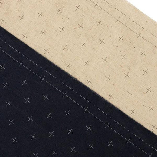a close-up view of a fabric with a diagonal pattern of white crosses on a beige background.