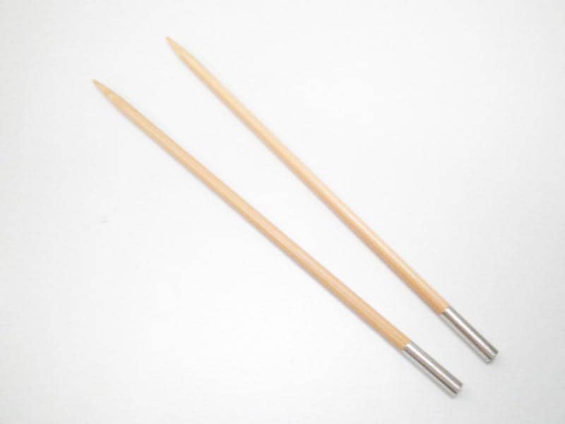 Two wooden knitting needles with silver tips are lying parallel to each other on a white background.