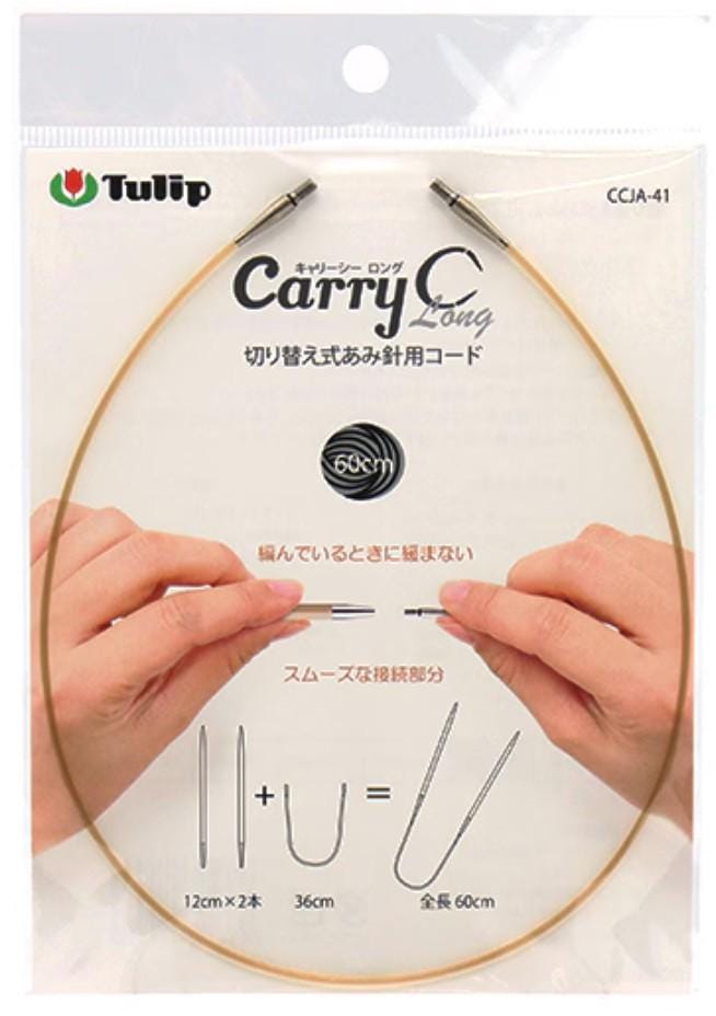 a pair of hands holding a gold-colored knitting needle with a clear plastic package featuring a diagram and text.