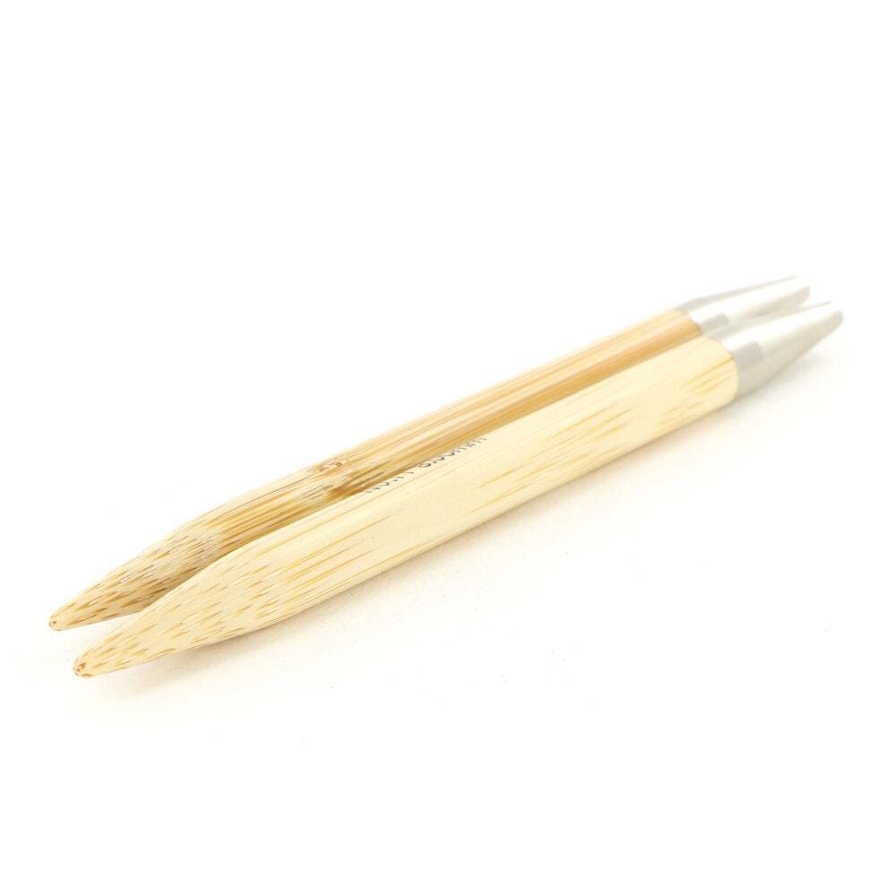 A pair of wooden knitting needles with silver tips, lying on a white background.