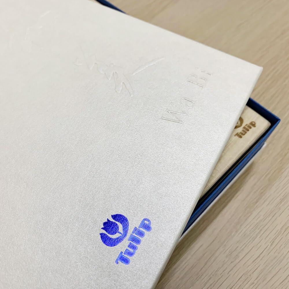 a close-up view of a white book or folder with a blue logo on the cover, placed on a wooden surface.