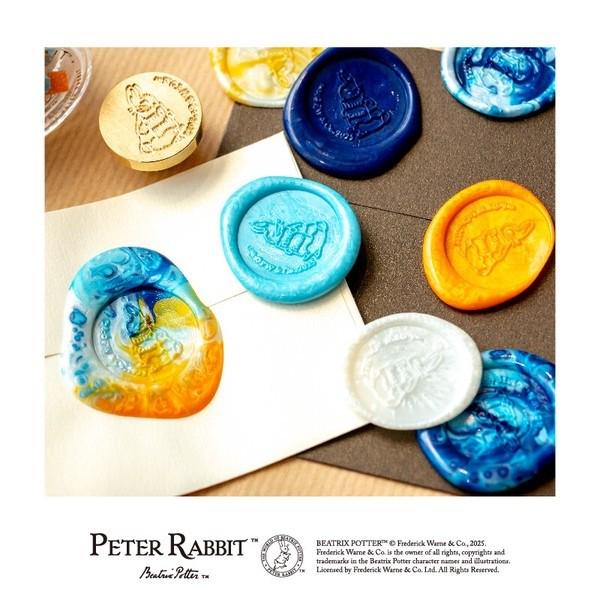 a collection of colorful wax seals and stamps, including a Peter Rabbit seal, arranged on a wooden surface.
