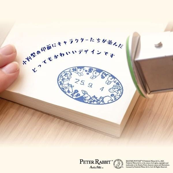 A hand holding a stamp with a blue and white design, and a stamping machine is visible in the background.