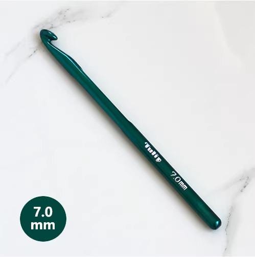 A green crochet hook with a 7.0 mm hook size is shown on a white marble surface.