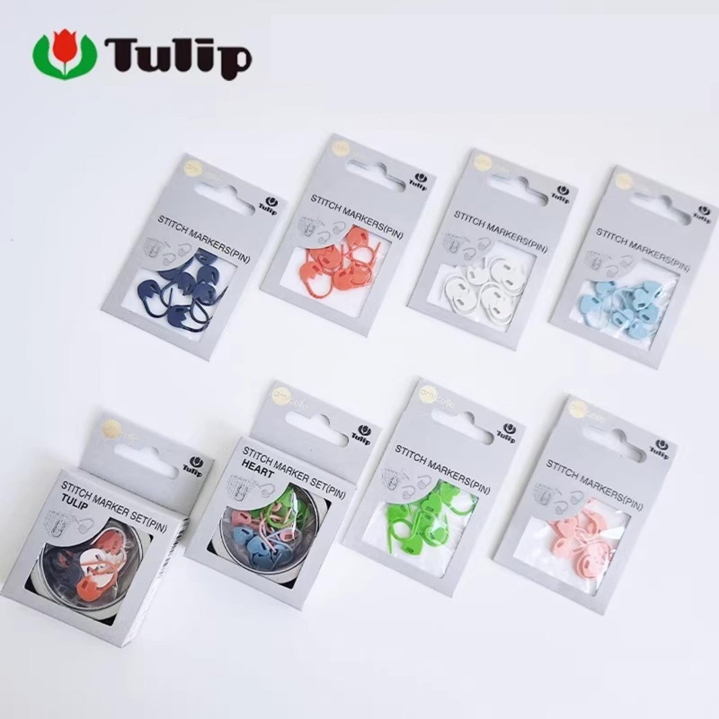 A collection of eight packages of sewing thread markers, each with a different color and pattern, arranged on a white background.