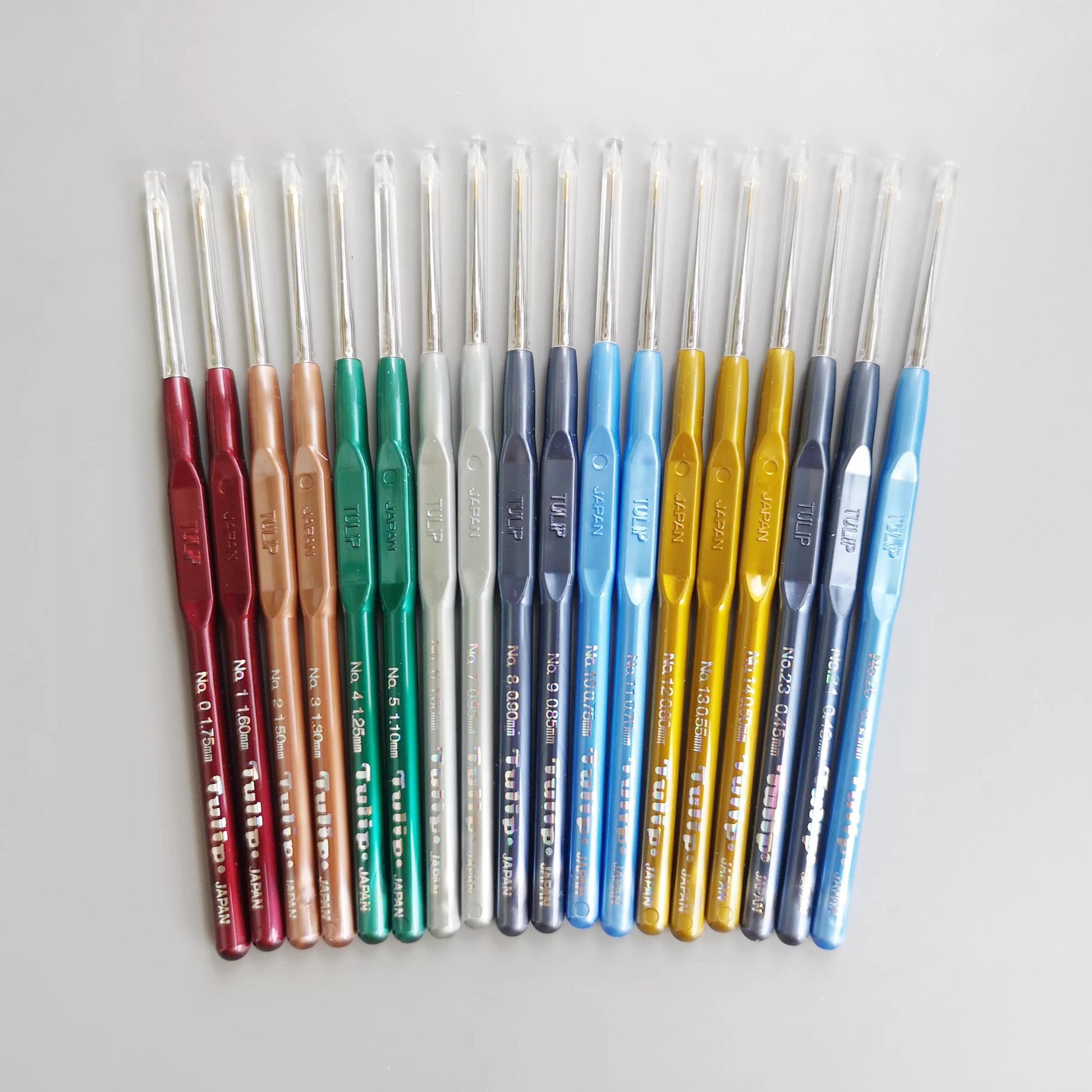 A collection of colorful crochet hooks arranged in a row on a white background.