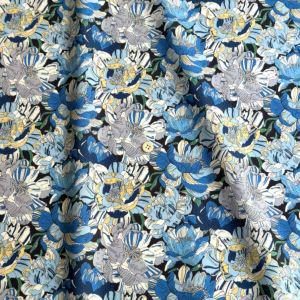 a close-up view of a fabric with a repeating pattern of blue and white flowers. The pattern is intricate and detailed, with the flowers varying in size and shape. The fabric appears to be made of a soft, plush material, suitable for clothing or home decor.