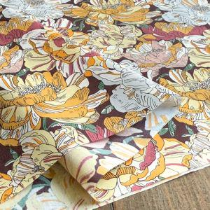 a close-up view of a fabric with a vibrant floral pattern in shades of yellow, orange, and white. The pattern is composed of various flowers and leaves, creating a visually striking and colorful design.