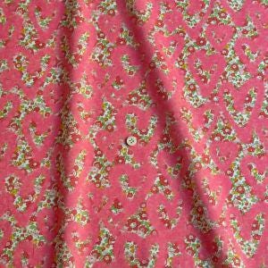a close-up view of a fabric with a floral pattern in shades of pink and green.