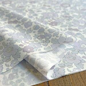 a close-up view of a fabric with a floral pattern, featuring a mix of light and dark shades of blue and gray.