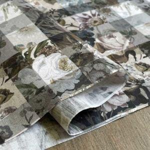 a close-up view of a fabric with a floral pattern, including various shades of green, white, and brown.