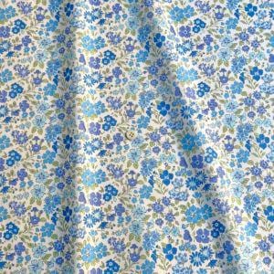a close-up view of a fabric with a floral pattern in shades of blue and white. The fabric appears to be made of a soft, light-colored material, possibly cotton or linen. The pattern consists of various blue flowers and leaves, creating a visually appealing and intricate design.