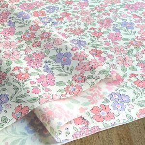 a close-up view of a fabric with a floral pattern in shades of pink, purple, and white. The fabric appears to be folded or rolled, with the pattern repeating across the surface.