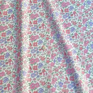 a close-up view of a fabric with a floral pattern in shades of pink, purple, and green. The fabric appears to be made of cotton and has a crinkled texture, giving it a soft and delicate appearance.