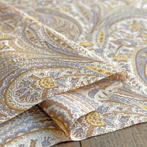 a close-up view of a fabric with a paisley pattern in shades of brown, white, and yellow.