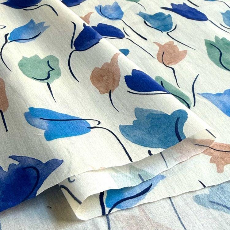 a close-up view of a fabric with a repeating pattern of blue and green flowers.