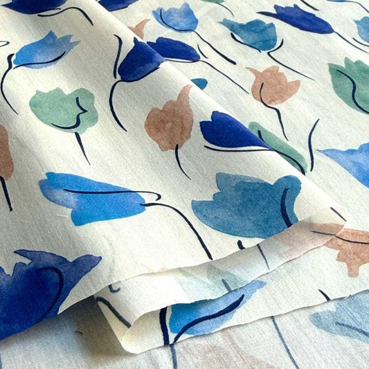 a close-up view of a fabric with a repeating pattern of blue and green flowers.