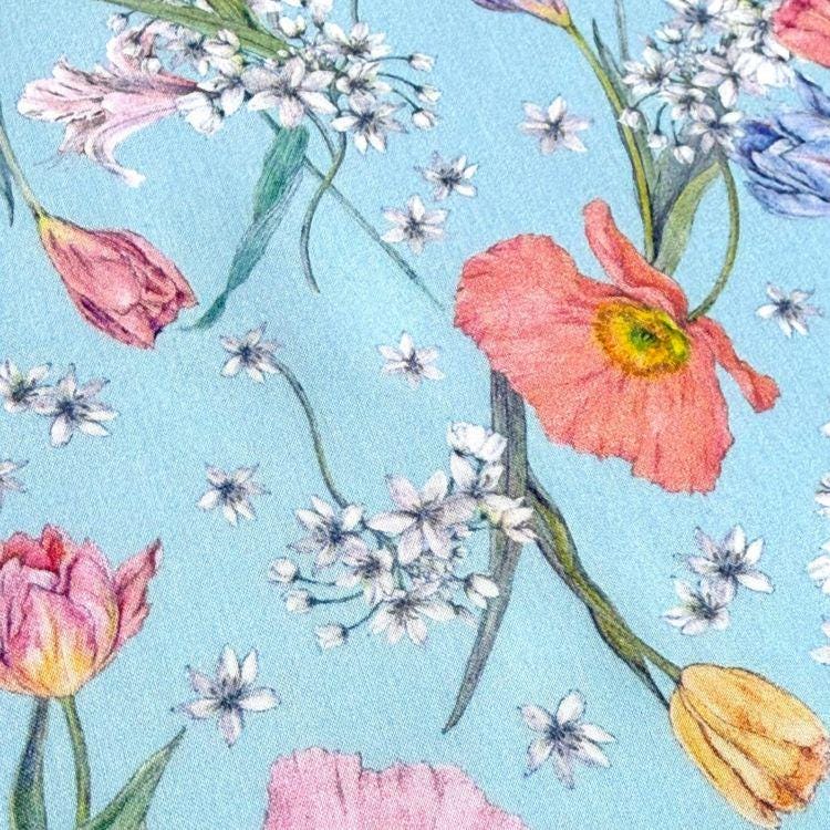 a vibrant and colorful floral pattern with various types of flowers, including tulips, daisies, and other blooms, against a light blue background.