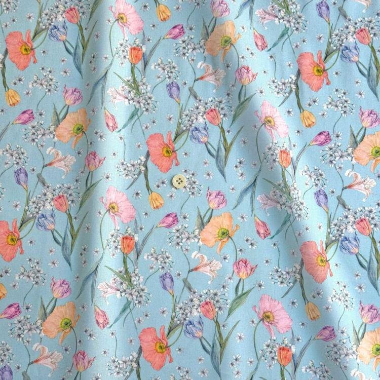 a repeating pattern of colorful flowers and leaves on a light blue background.