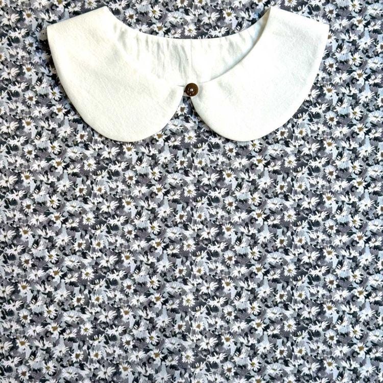 a white collar with a button, set against a background of a floral print fabric.