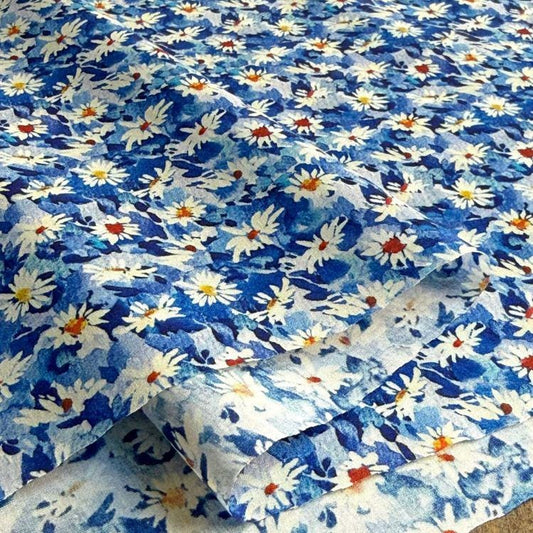 a close-up view of a fabric with a blue and white floral pattern. The fabric appears to be folded or rolled, revealing the intricate design of the flowers.