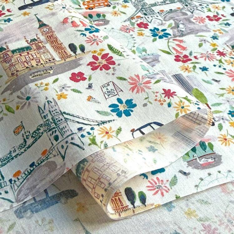 a close-up view of a fabric with a colorful, printed pattern of various landmarks and cityscapes, including London's Big Ben, the Eiffel Tower, and other iconic structures.