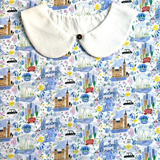 a white collar with a button, set against a background with a repeating pattern of various landmarks and cityscapes, including London landmarks such as Big Ben, the London Eye, and the Houses of Parliament.