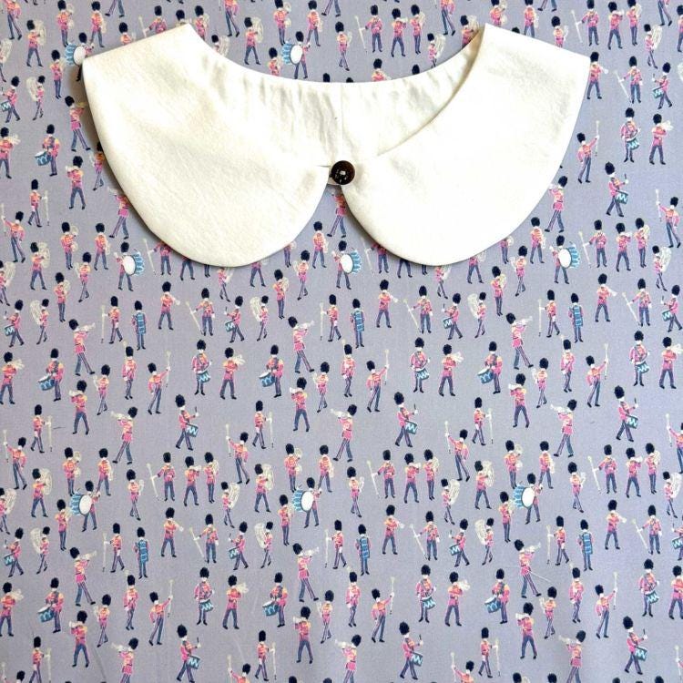a white collar with a black button, placed on a background with a repeating pattern of people playing musical instruments.