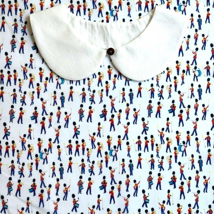 a white collar with a button, placed on top of a background with a repeating pattern of soldiers in red, blue, and yellow uniforms.