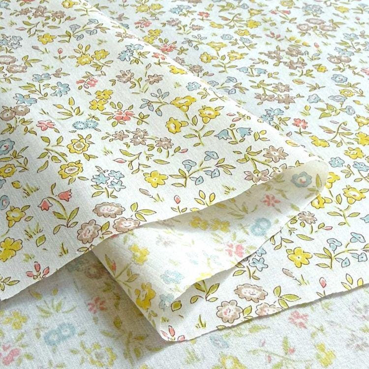 a close-up view of a fabric with a floral pattern, featuring various shades of yellow, pink, and blue flowers and leaves.