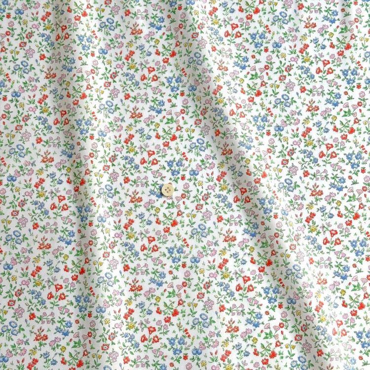 a close-up view of a fabric with a floral pattern in various colors, including red, blue, green, and yellow. The fabric appears to be made of cotton and has a slightly wrinkled texture.