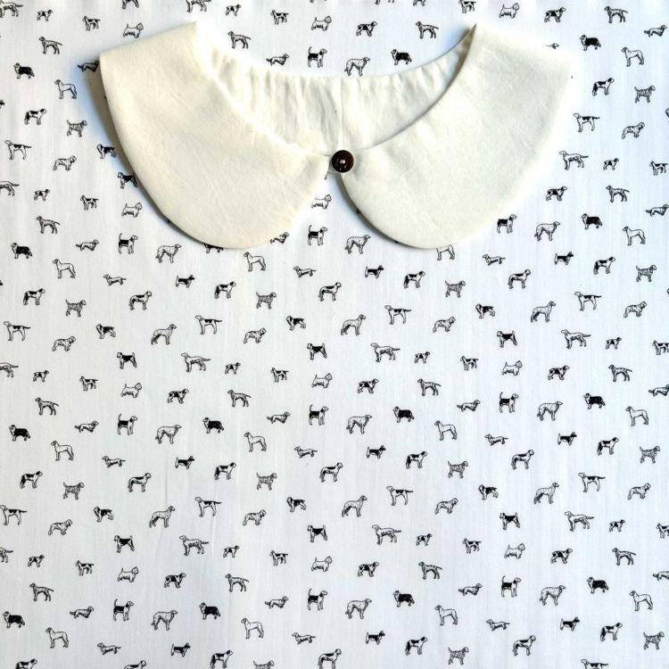 a white collar with a button, placed on a background with a repeating pattern of black and white dog illustrations.