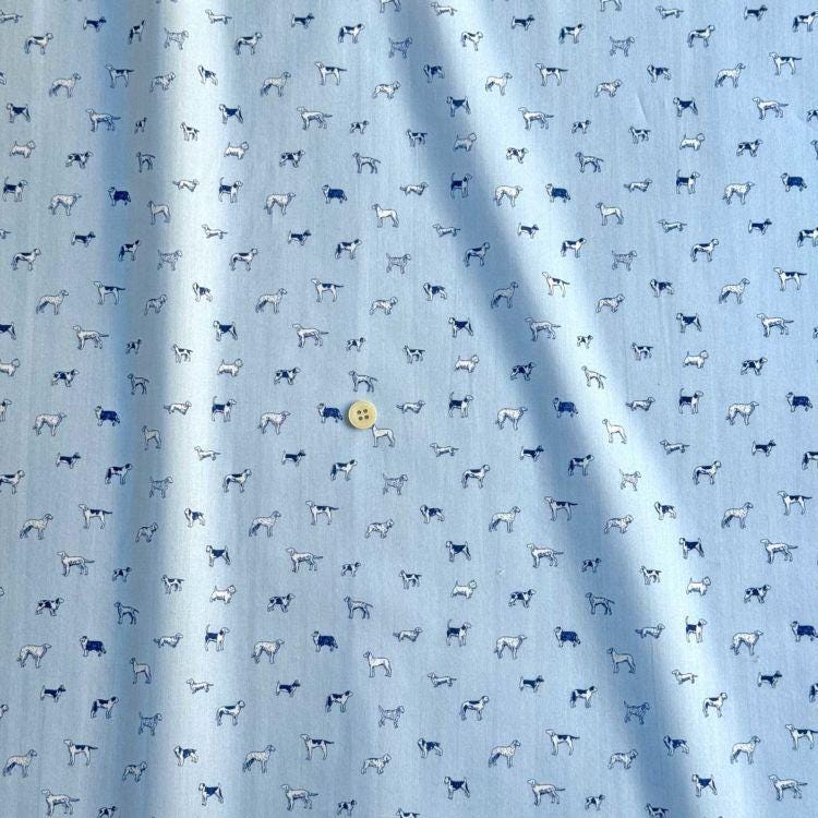 a fabric with a repeating pattern of small white dogs printed on it. The dogs are arranged in a diagonal pattern across the fabric, creating a visually interesting and playful design.