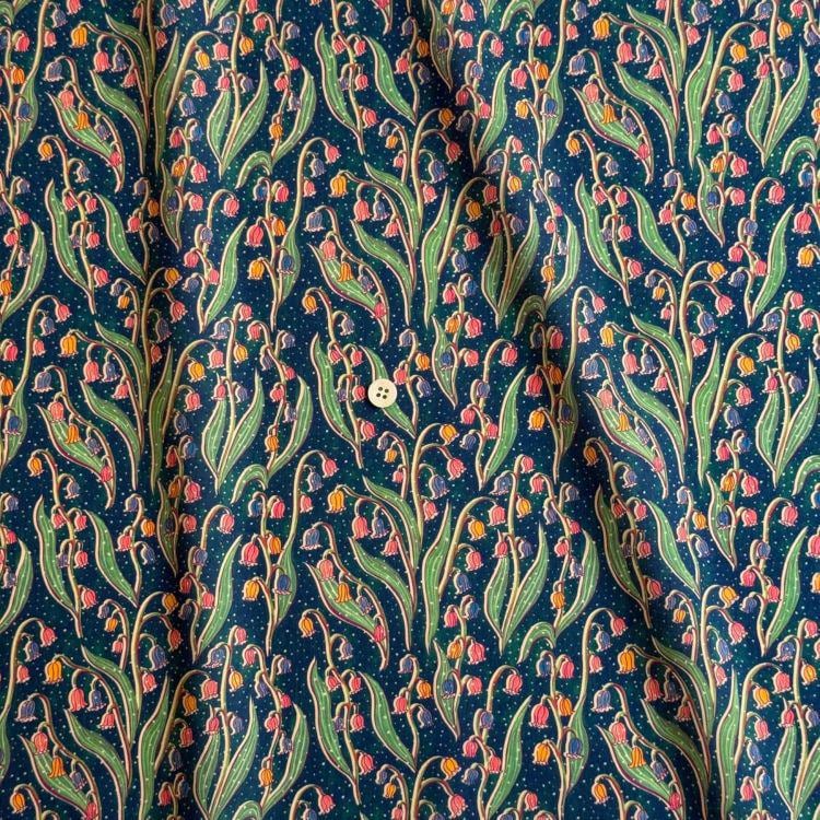 a close-up view of a fabric with a repeating pattern of green leaves and pink flowers. The pattern is vibrant and detailed, creating a visually striking design.