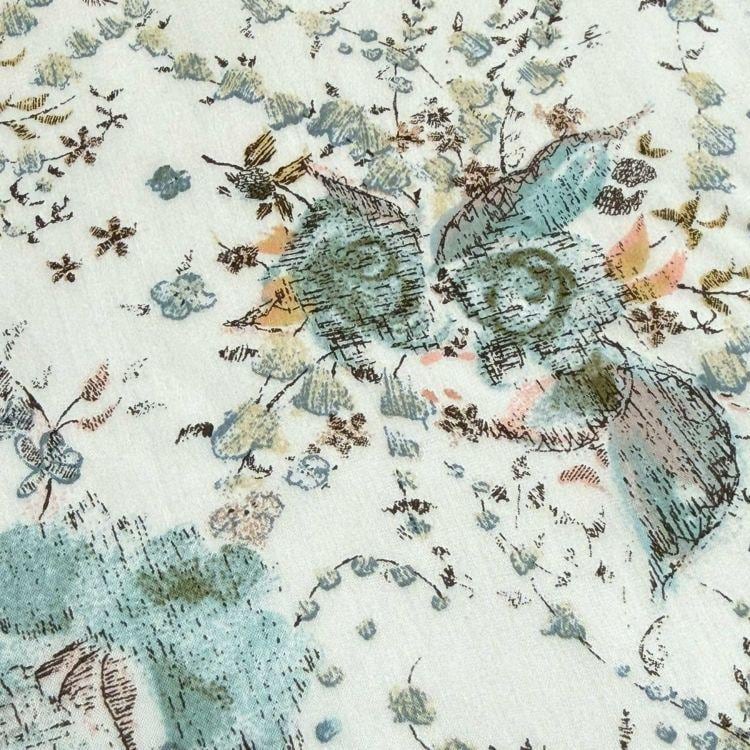 The image is a close-up of a fabric with a floral pattern, featuring various shades of green, blue, and brown. The pattern includes leaves, flowers, and other natural elements, creating a visually appealing and intricate design.