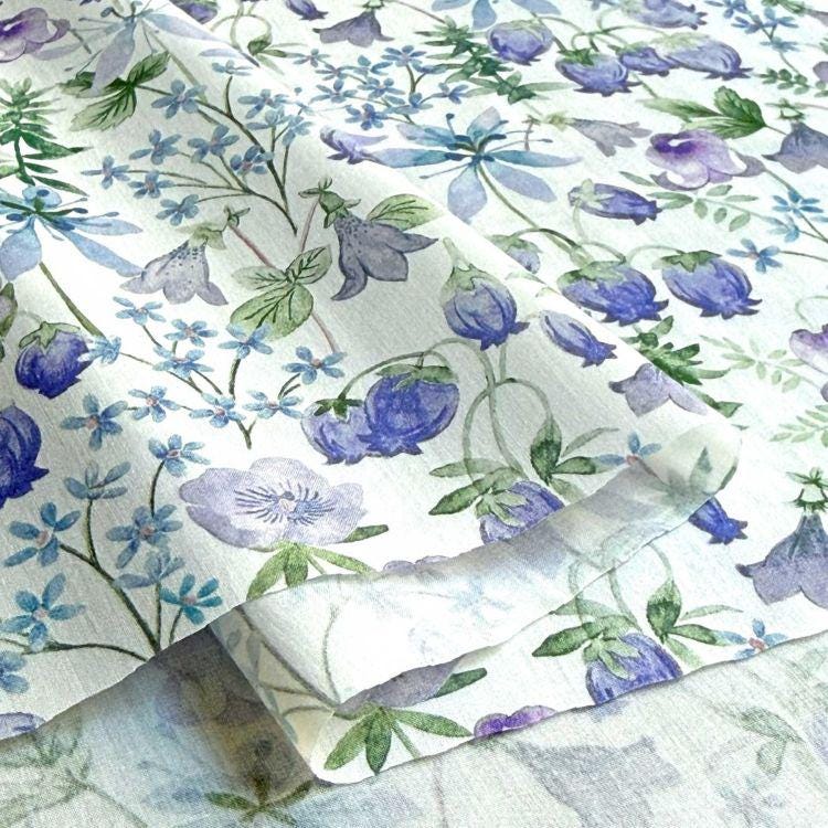 a close-up view of a fabric with a floral pattern, including various shades of blue and purple flowers and leaves.