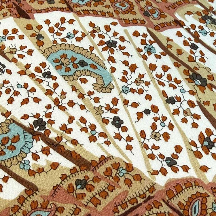 a close-up view of a fabric with a floral pattern in shades of brown, white, and blue. The pattern is intricate and detailed, with various shapes and designs that create a visually appealing and textured appearance.