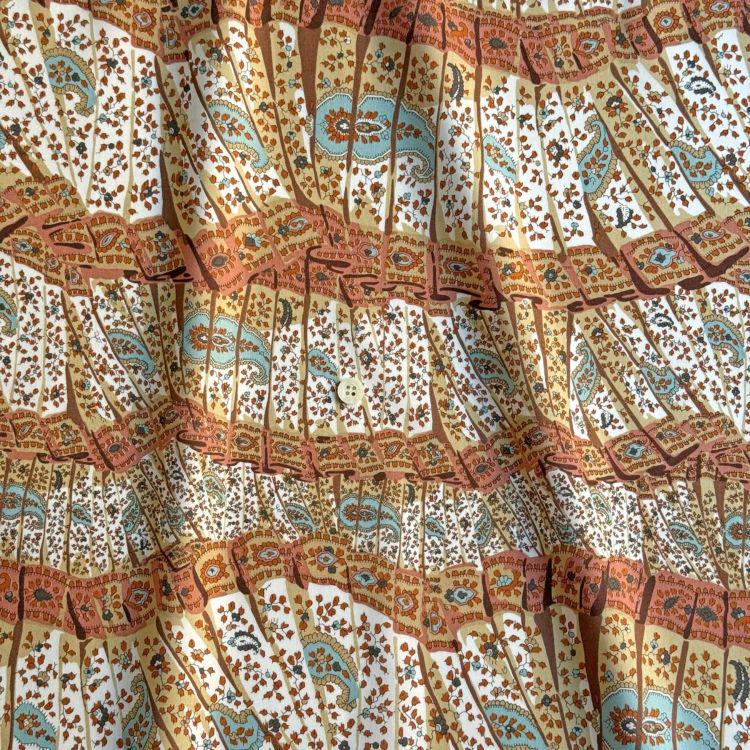 The image is a close-up of a fabric with a repeating pattern of colorful stripes and floral designs. The pattern is vibrant and eye-catching, with a mix of warm and cool colors. The fabric appears to be made of a soft, textured material, suitable for clothing or home decor.