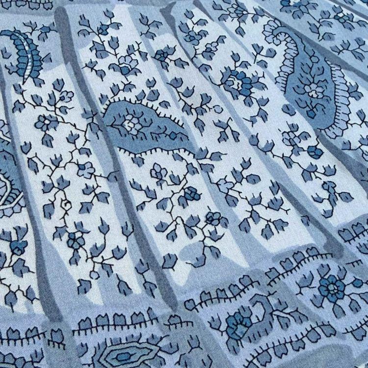a close-up view of a patterned fabric with a repeating floral design in shades of blue and gray.